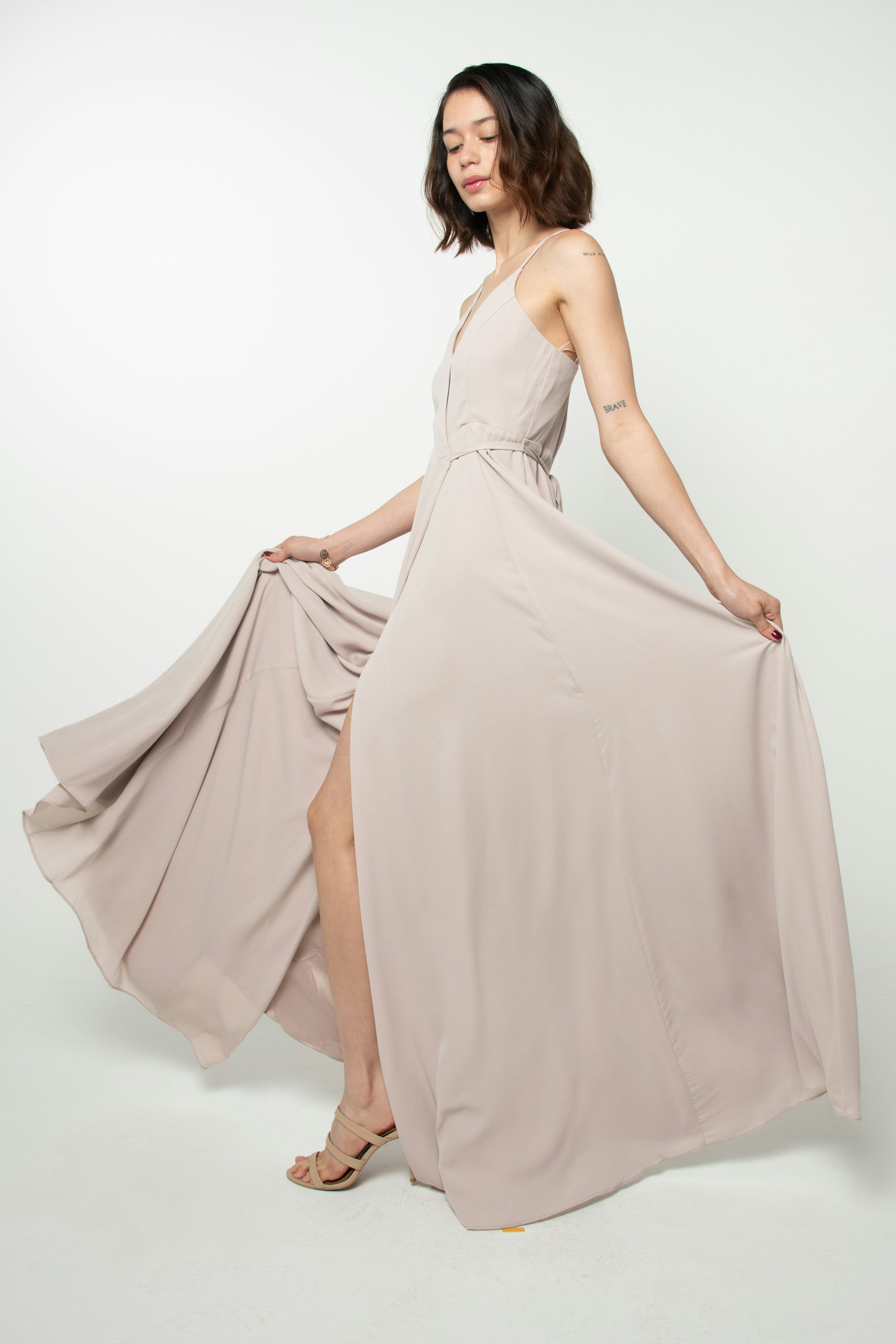 Woman wearing a flowing neutral beige designer maxi dress